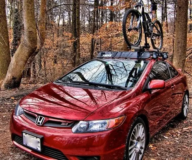 A Bicycle above a red car in trees