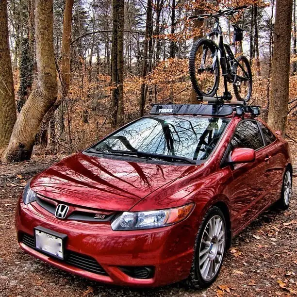 A Bicycle above a red car in trees